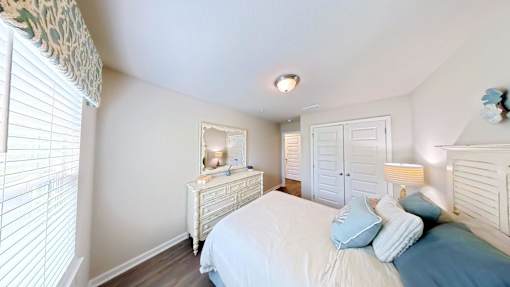 A bedroom with a bed, dresser, and mirror.