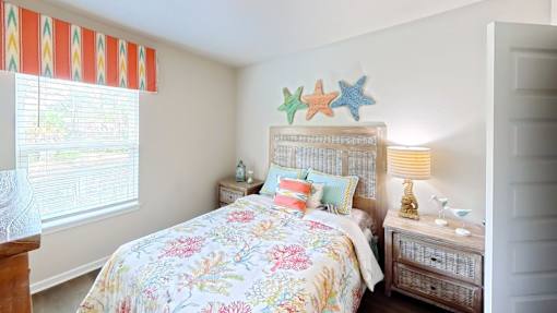 A bedroom with a floral bedspread and a wooden nightstand.