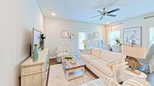A living room with a white couch, a wooden cabinet, and a ceiling fan.