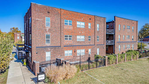 A red brick building with a black fence in front.