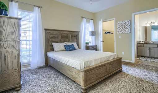 A bedroom with a large bed and a wooden dresser.