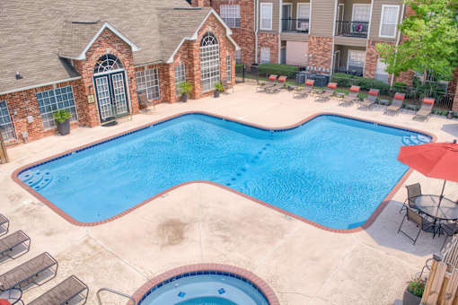 A large outdoor swimming pool surrounded by lounge chairs and umbrellas.