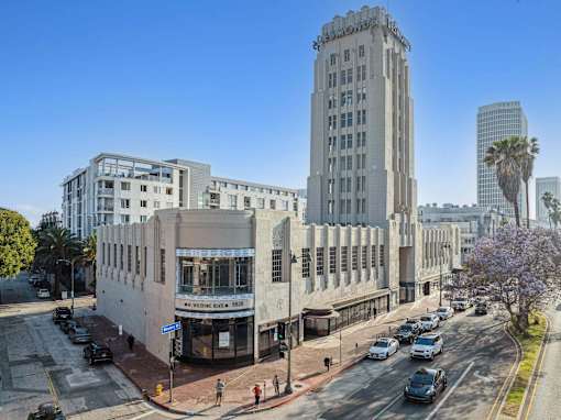 A street view of a city with a tall building in the center.
