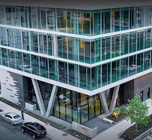 A modern building with glass windows and a tree in front.