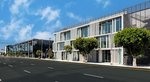 A modern building with a glass facade is situated on a street with a clear blue sky above.