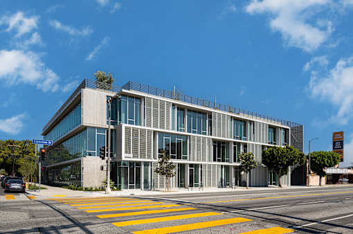 A modern building with a glass facade and a yellow crosswalk in front.