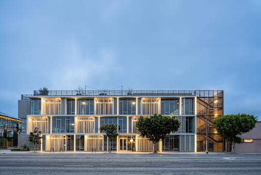 A modern building with a glass facade and a tree in front of it.