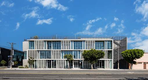 A modern building with a glass facade and trees in front.