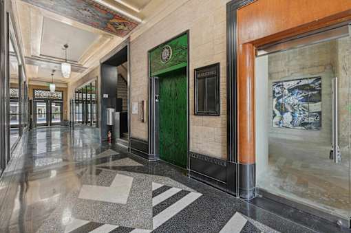 A hallway with a green door and a black and white floor.