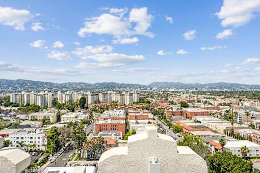 A cityscape with a large building in the foreground and mountains in the distance.