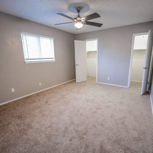 A room with a ceiling fan and carpeted floor.