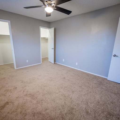 A room with a ceiling fan and carpeted floor.