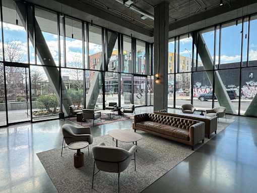 A large room with a couch, chairs, and tables with a view of the outside.