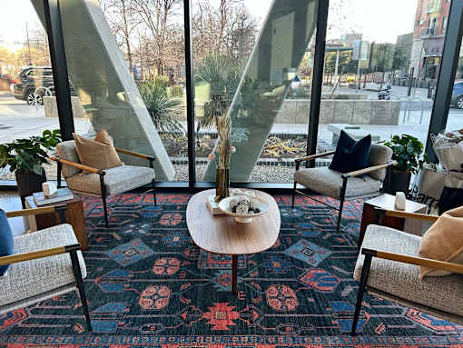 A room with a glass wall and a rug with a floral pattern.