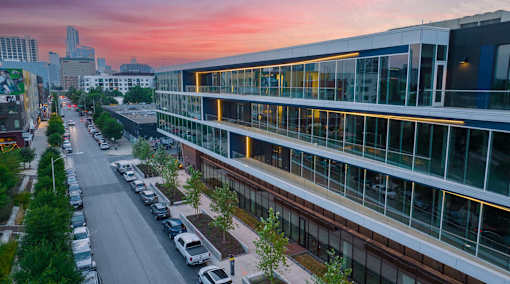 A parking lot with cars and a building with large windows.