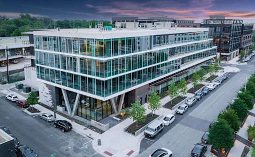 A modern glass building with cars parked in front.