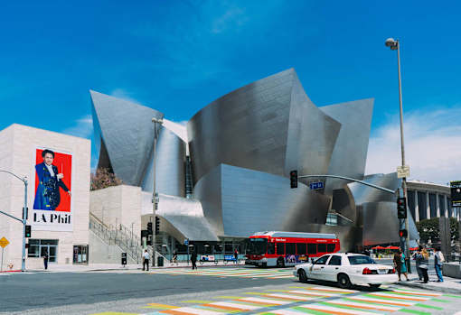 A modern building with a curved facade and a large poster of a man in a suit on the side of a building.
