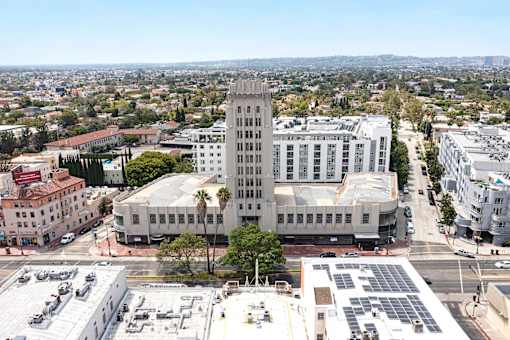 A large white building with a tower sits in the middle of a city.