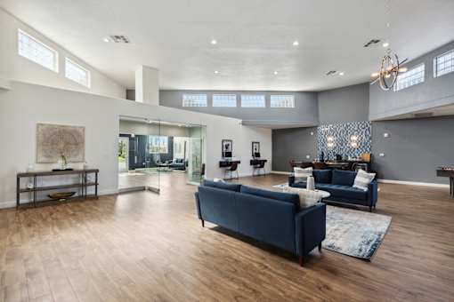 A spacious living room with a dark blue sofa and wooden flooring.