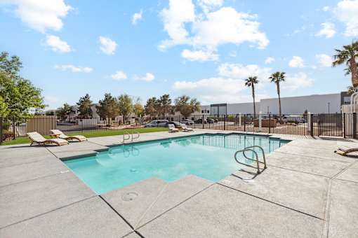 A swimming pool surrounded by a concrete patio and palm trees.