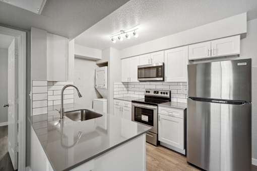 A modern kitchen with stainless steel appliances and white cabinetry.