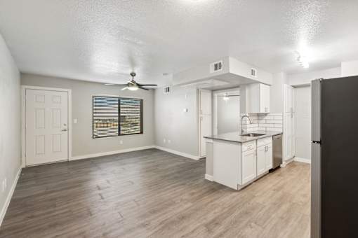 A spacious room with a kitchenette and a ceiling fan.