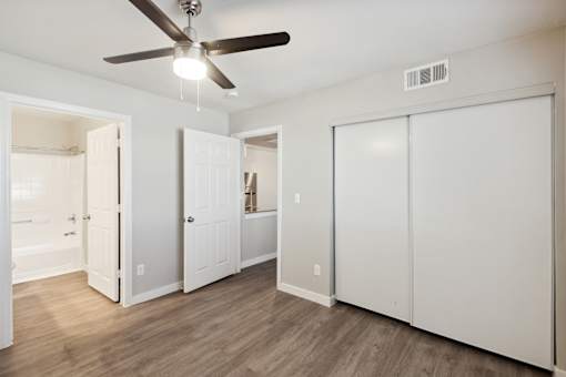 A room with a ceiling fan and white doors.