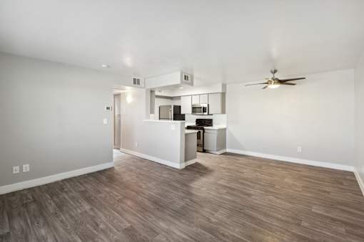 A room with a ceiling fan and a kitchenette.