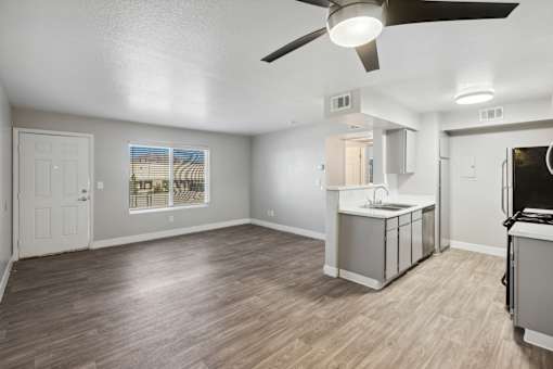 A room with a ceiling fan and a kitchenette.