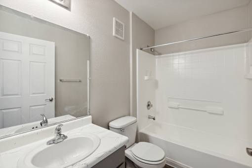A white bathroom with a toilet, sink, and bathtub.