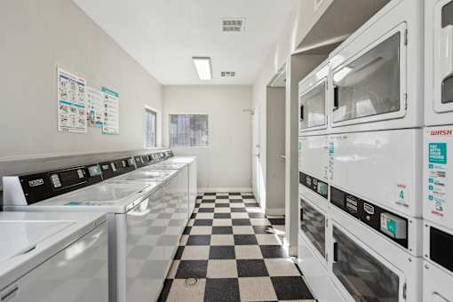 A laundromat with a checkered floor and rows of washers and dryers.