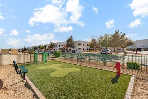 A playground with a green bench, a red fire hydrant, and a tennis court.