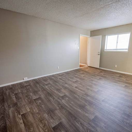 A room with wooden flooring and a doorway leading to another room.