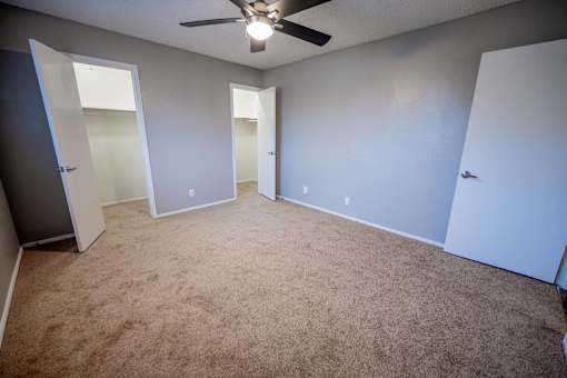 A room with a ceiling fan and carpeted floor.