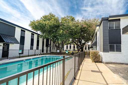 A pool is surrounded by a fence and a walkway.
