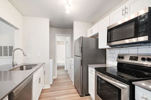 A kitchen with white cabinets and black appliances.