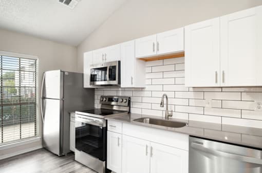 A kitchen with white cabinets and stainless steel appliances.