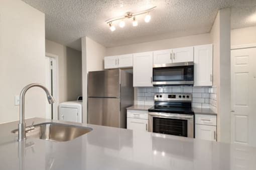 A kitchen with a stainless steel sink and refrigerator.