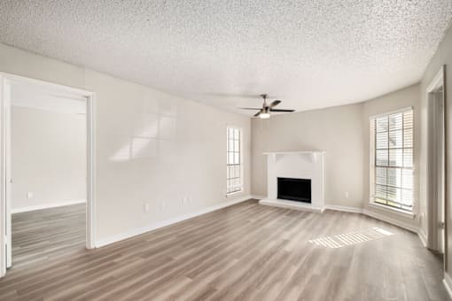 A spacious living room with a fireplace and a ceiling fan.