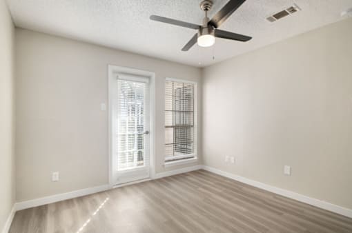 A room with a ceiling fan and a door leading to a balcony.