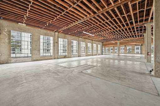 A large empty room with wooden ceiling and concrete floor.