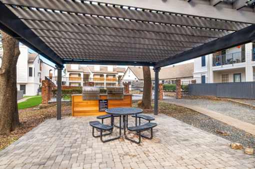 A patio with a table and benches under a black canopy.