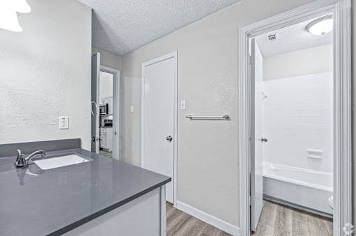 A bathroom with a sink, mirror, and bathtub.
