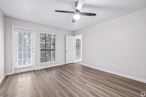 A room with a ceiling fan and two windows with blinds.