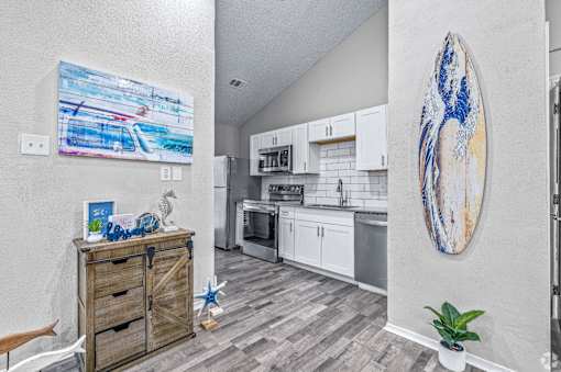 A kitchen with a surfboard picture on the wall.