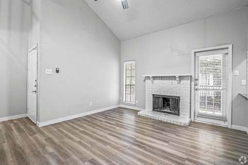 A room with a fireplace and wood flooring.