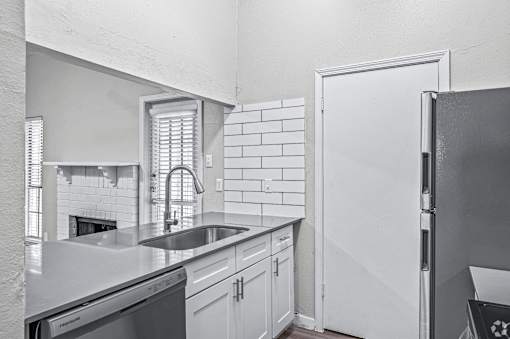 A kitchen with white cabinets and a black refrigerator.