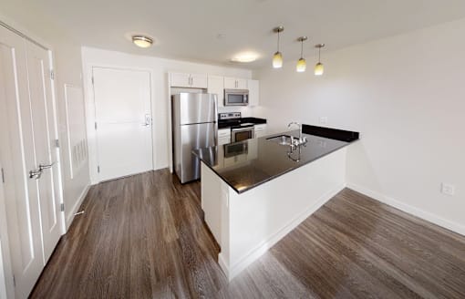 A kitchen with a refrigerator, microwave, and oven.