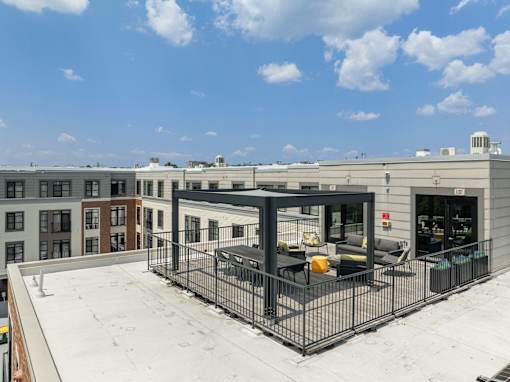 A rooftop patio with a black metal fence and a table and chairs, 28 Austin, Newton, Massachusetts