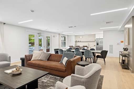 A modern living room with a brown couch, grey armchairs, and a wooden coffee table.